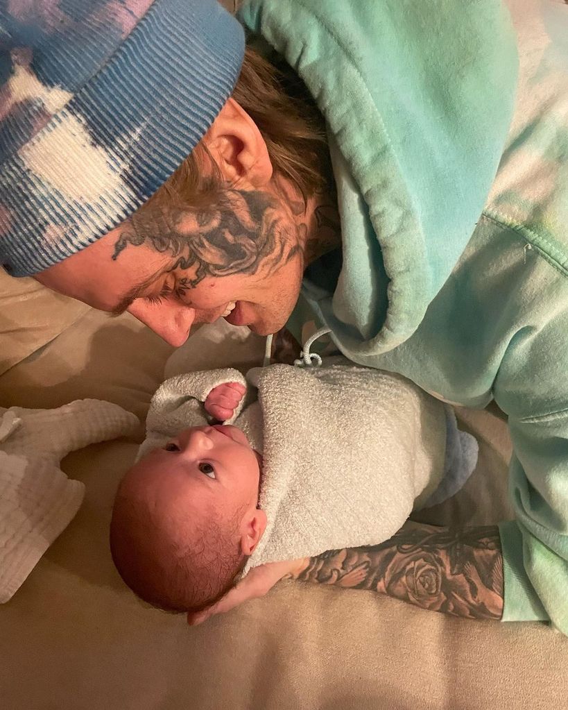 Aaron Carter cuddles his newborn son who is lying on the floor 