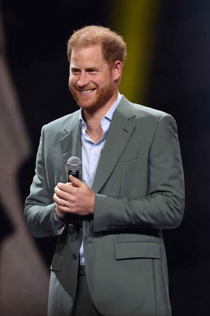 Prince Harry in grey suit holding a microphone