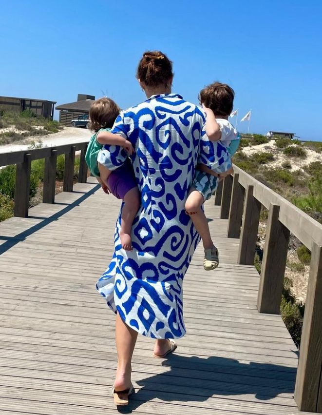 Princesa Eugenie em um vestido branco e azul carregando dois meninos