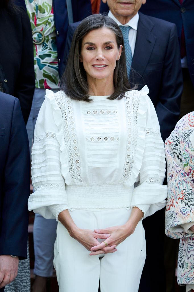 Queen Letizia wearing a white lace blouse with subtle ruffles and white trousers