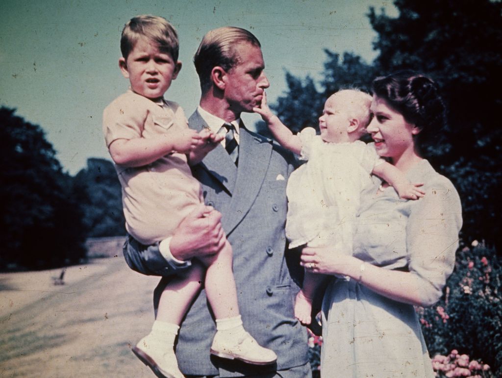 The Queen carrying a baby Princess Anne and Prince Philip carrying a young Prince Charles