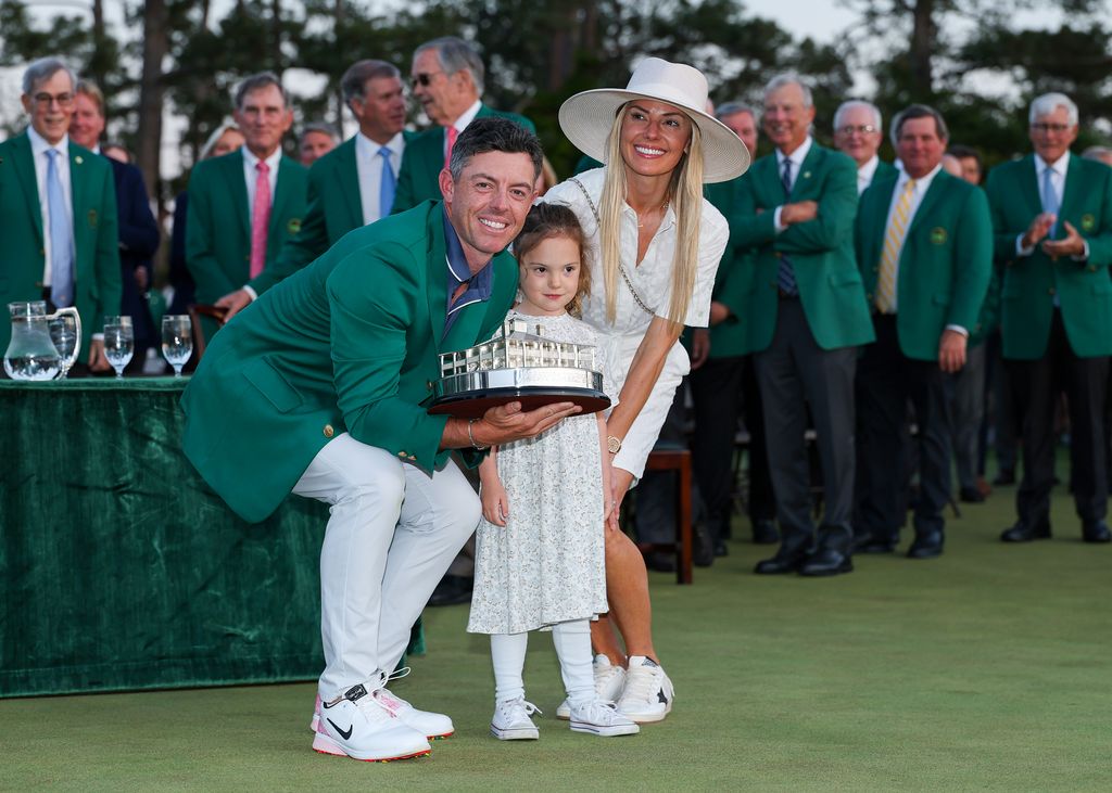 (L-R) Rory McIlroy of Northern Ireland poses with daughter Poppy and wife Erica Stoll holding the Masters trophy during the Green Jacket Ceremony after winning the 2025 Masters Tournament at Augusta National Golf Club on April 13, 2025 in Augusta, Georgia. (Photo by Richard Heathcote/Getty Images)