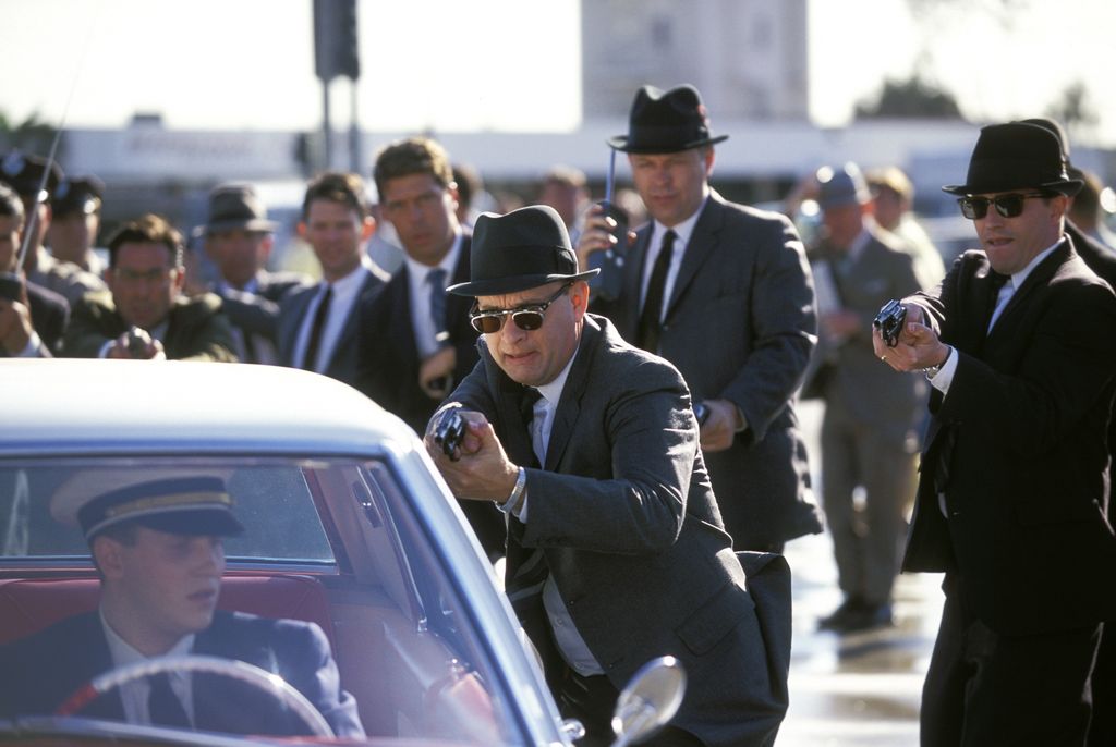 Still from Catch Me If You Can featuring Tom Hanks and agents pulling a gun on a man in a car