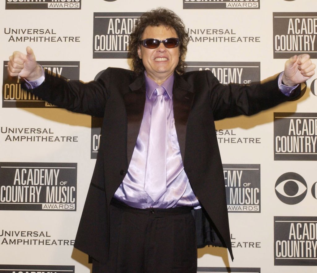 Ronnie Milsap wearing a purple silk shirt and suit, and sunglasses