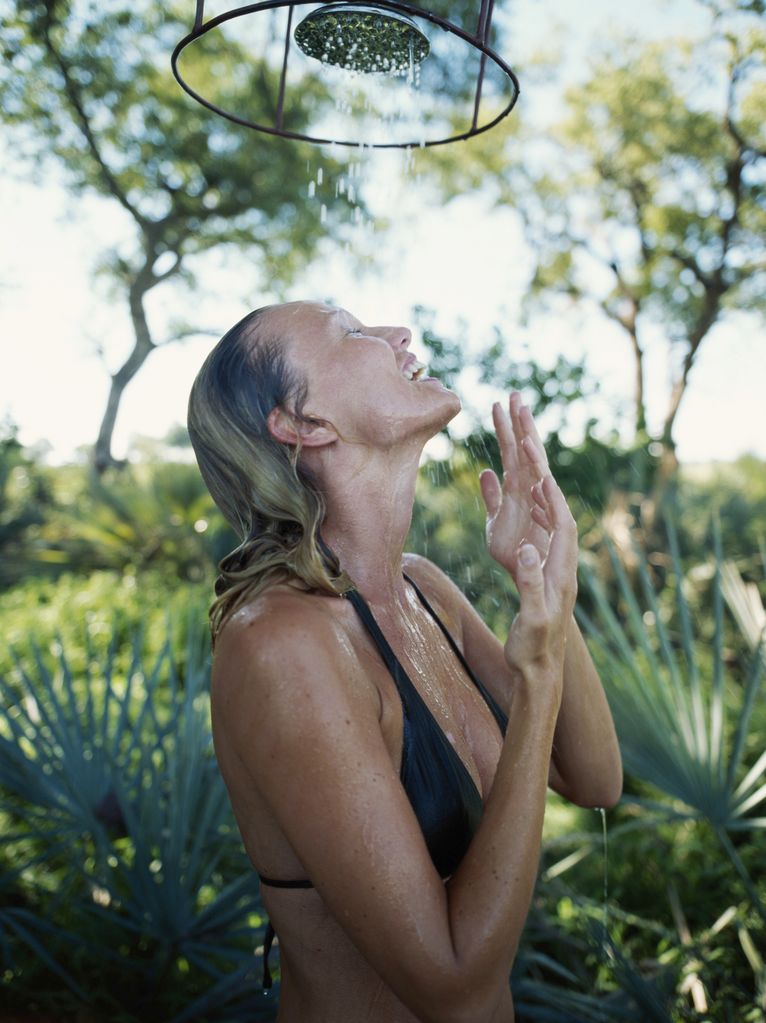 Woman in bikini showering outdoors, side view