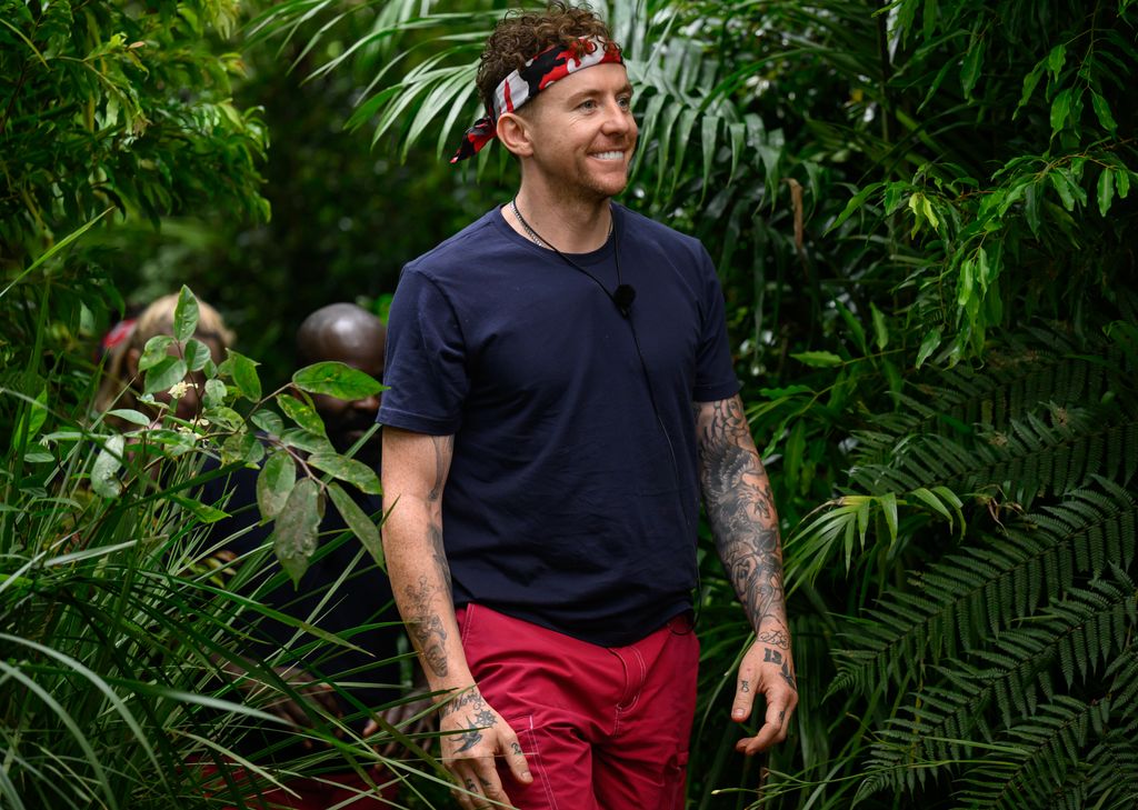 man in jungle wearing blue shirt and red shorts 