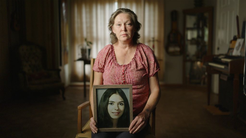 womans holds a photo frame sitting on chair