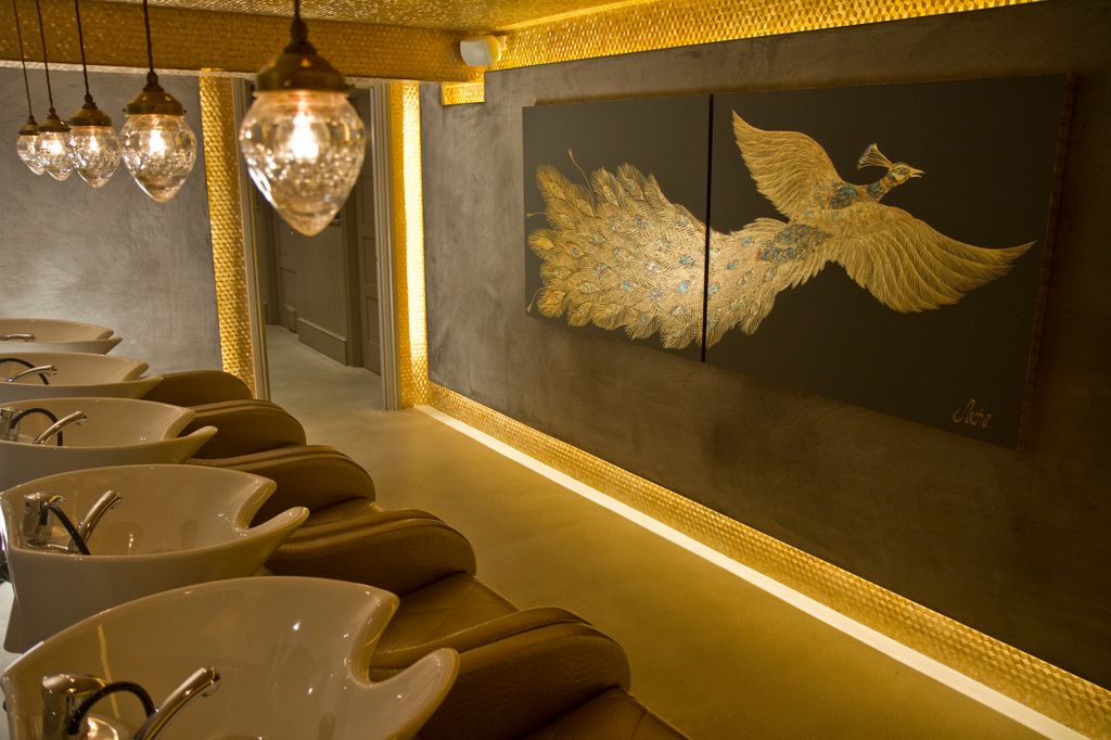 Taylor Taylor London wash area with gold decor, ambient lighting, peacock art, and plush seating.