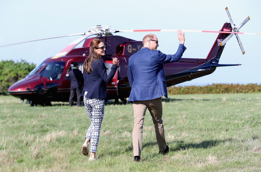 Prince William and Princess Kate wave as they head back to the Royal helicopter after visiting the Island of St Martin's in the Scilly Isles on September 2, 2016