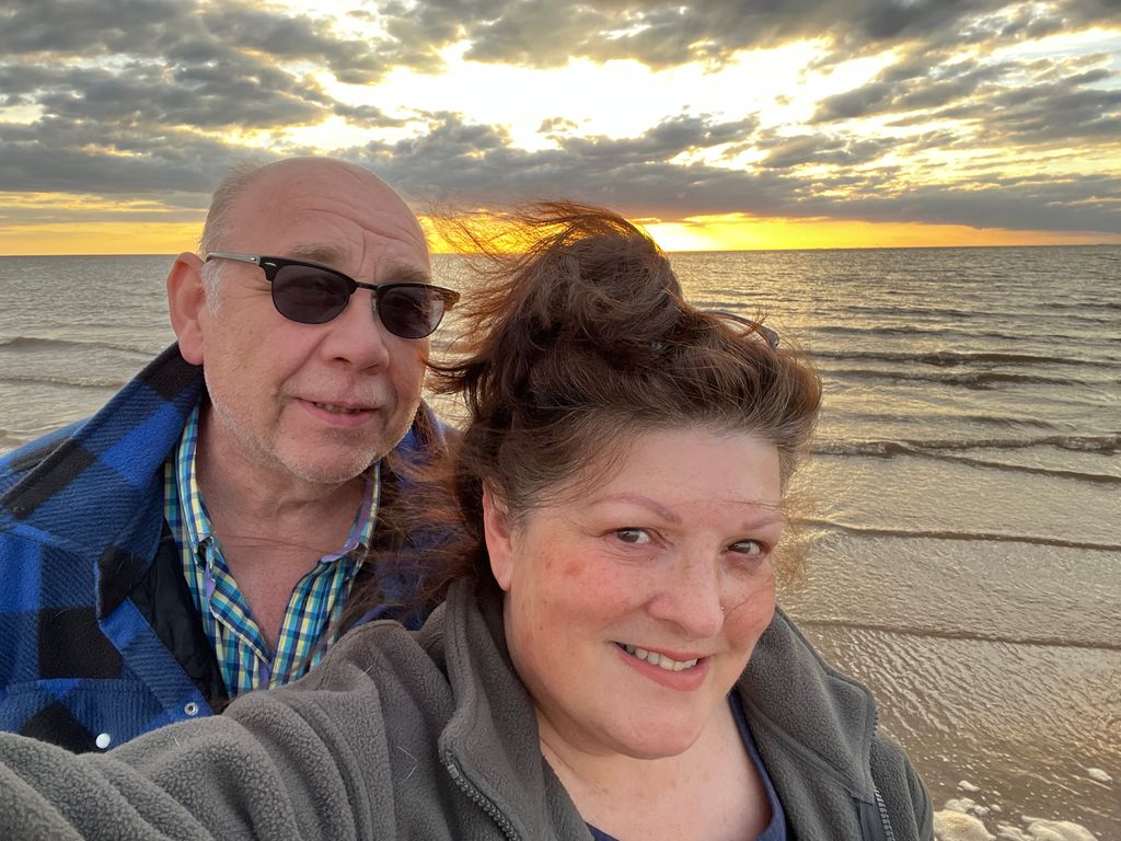 Couple smiling in front of a sunset