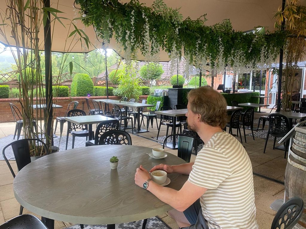 Man cradling coffee cup in outdoor dining area