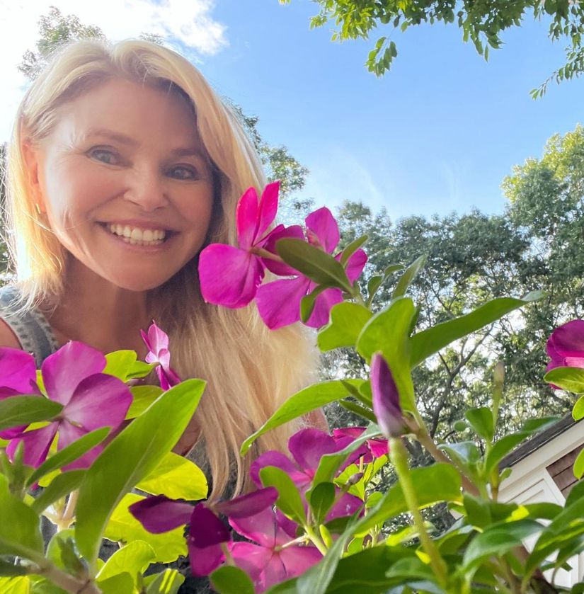 Christie Brinkley in a garden wearing dungarees