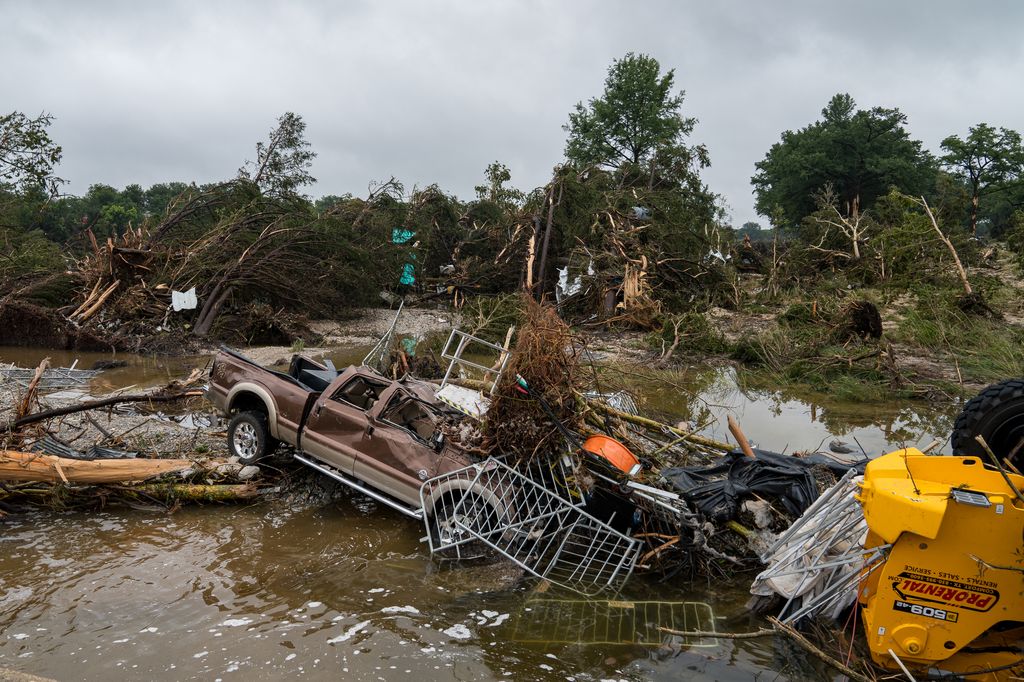photo of car and trees and debris in the water after texas flooding