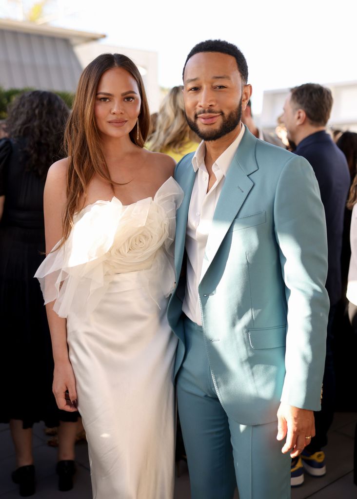 Chrissy in white silk with a floral crop top with john in blue suit