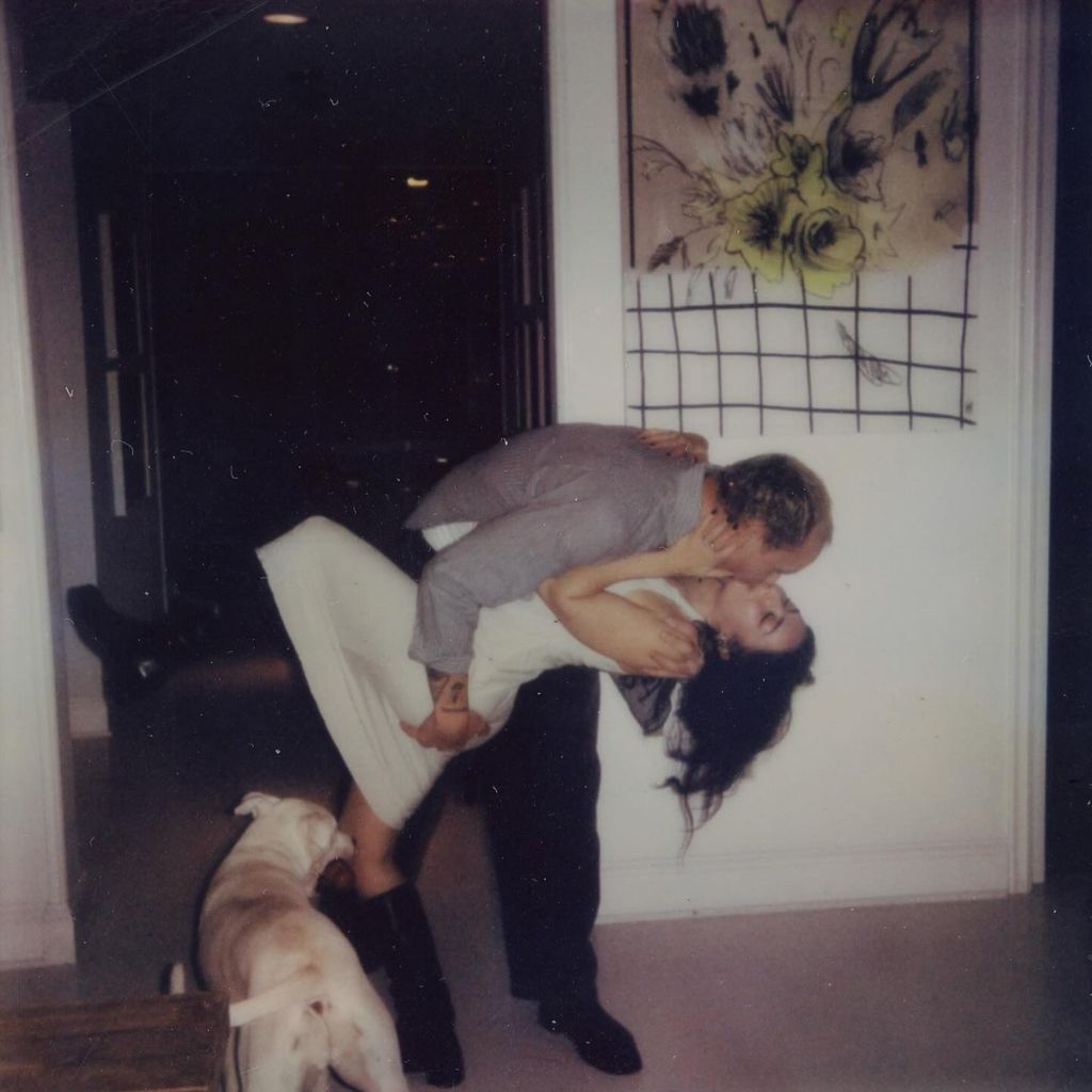 Charli and George kissing with a dog watching 