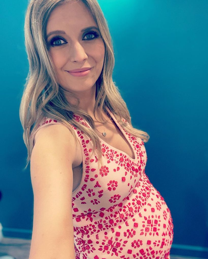 Pregnant Rachel Riley taking a selfie wearing her red and white bridal mini dress