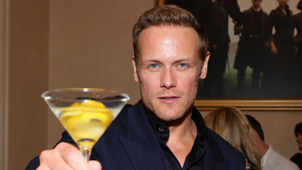 Sam Heughan raising a martini glass. 