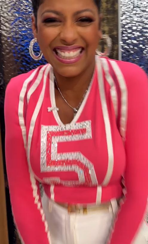 Tamron Hall in pink cheerleader outfit and cream pants