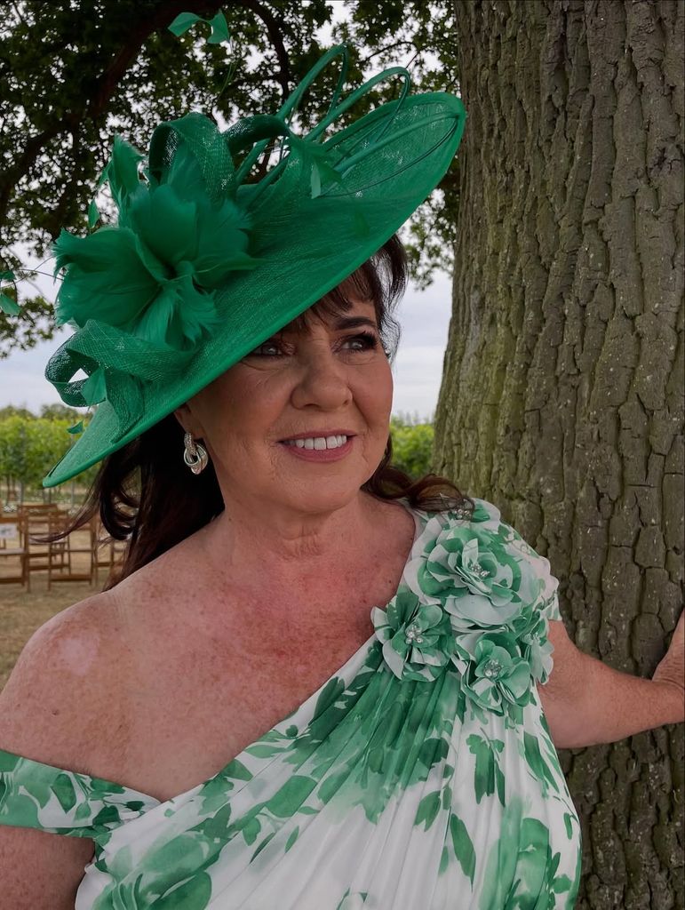 Coleen Nolan in a green one-shouldered dress and hat