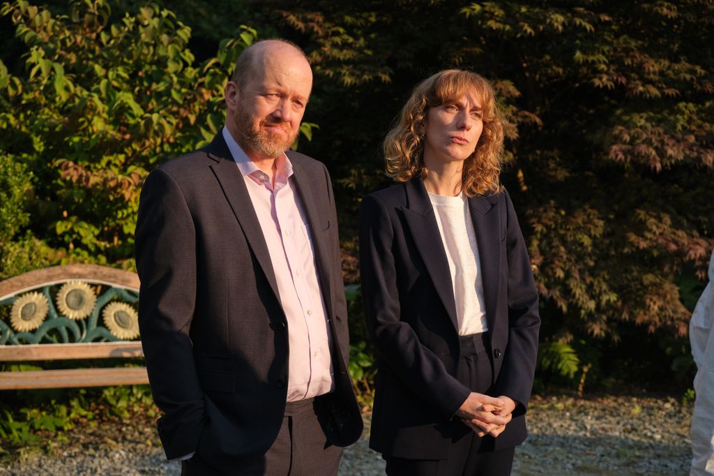 Man and woman standing in front of bench 