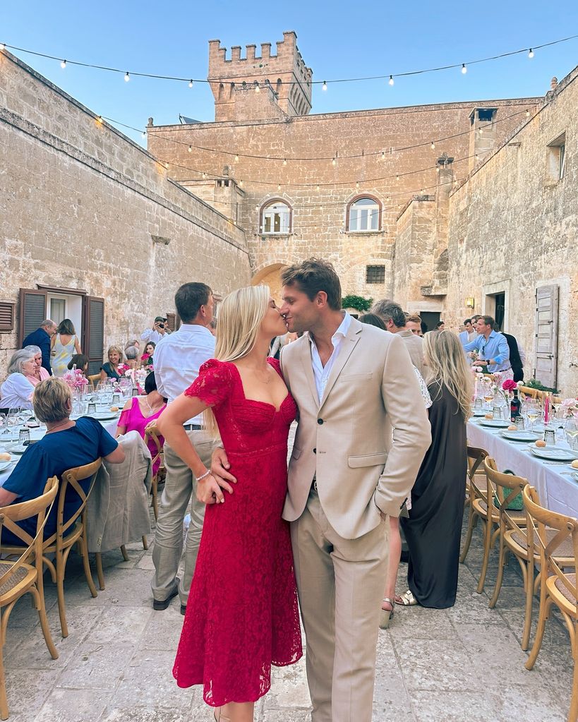 Amelia beijando marido em vestido vermelho