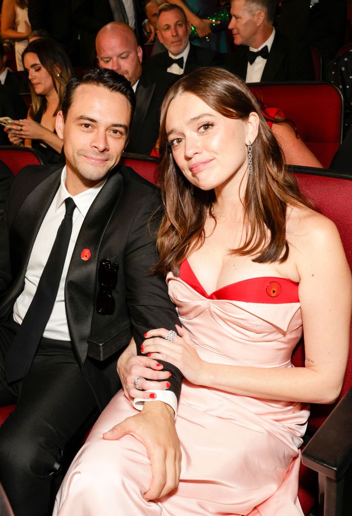 man in suit, woman in pink dress sitting together on red theatre seats
