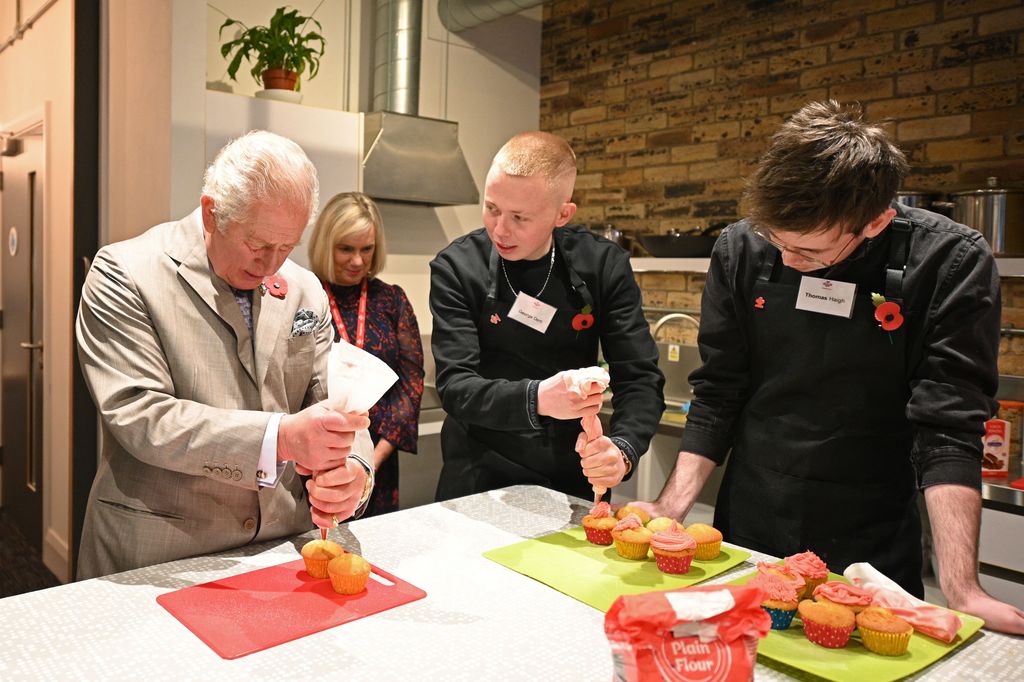 Charles trying his hand at decorating cupcakes with a group of young people taking a course named 'Explore' 