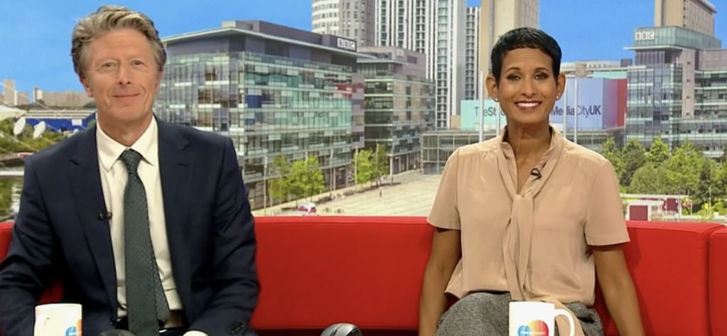 Naga Munchetty and Charlie Stayt smiling on red sofa bbc breakfast