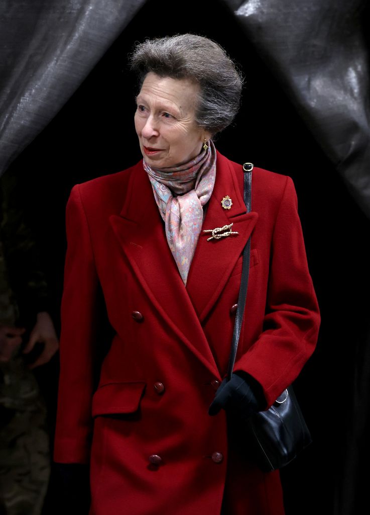 Princesa Anne usando um broche simbólico com um casaco vermelho 