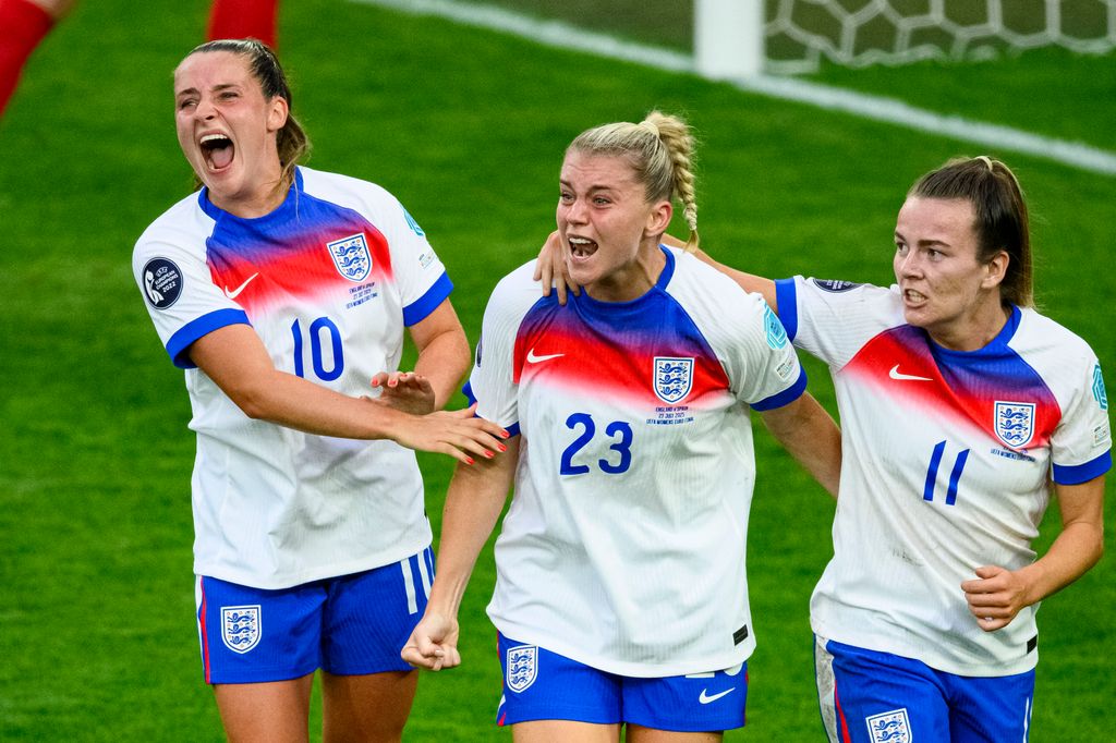 three female footballers on field cheering