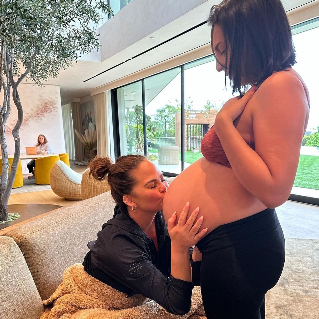 Chrissy Teigen kisses surrogate's baby bump