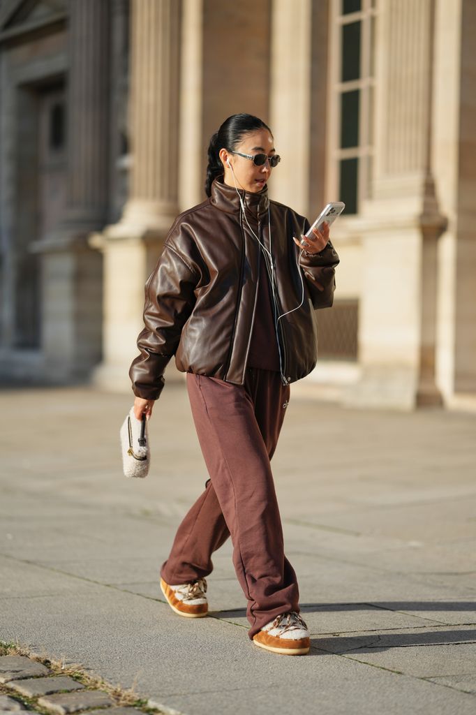 Yuwei Zhangzou in Paris wearing a brown padded leather jacket and brown trousers, brown and cream moon boots and a shearling handbag. 