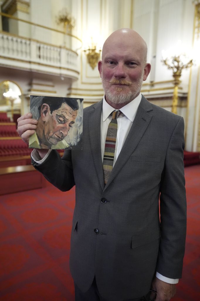 Artist Tom Halifax holds a painting which he gave to King Charles 