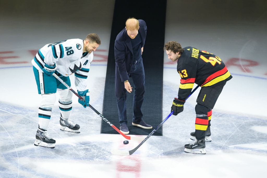 Prince Harry, The Duke of Sussex drops the puck during a ceremonial face-off with Quinn Hughes #43 of the Vancouver Canucks and Tomas Hertl #48 of the San Jose Sharks prior to their NHL game at Rogers Arena 