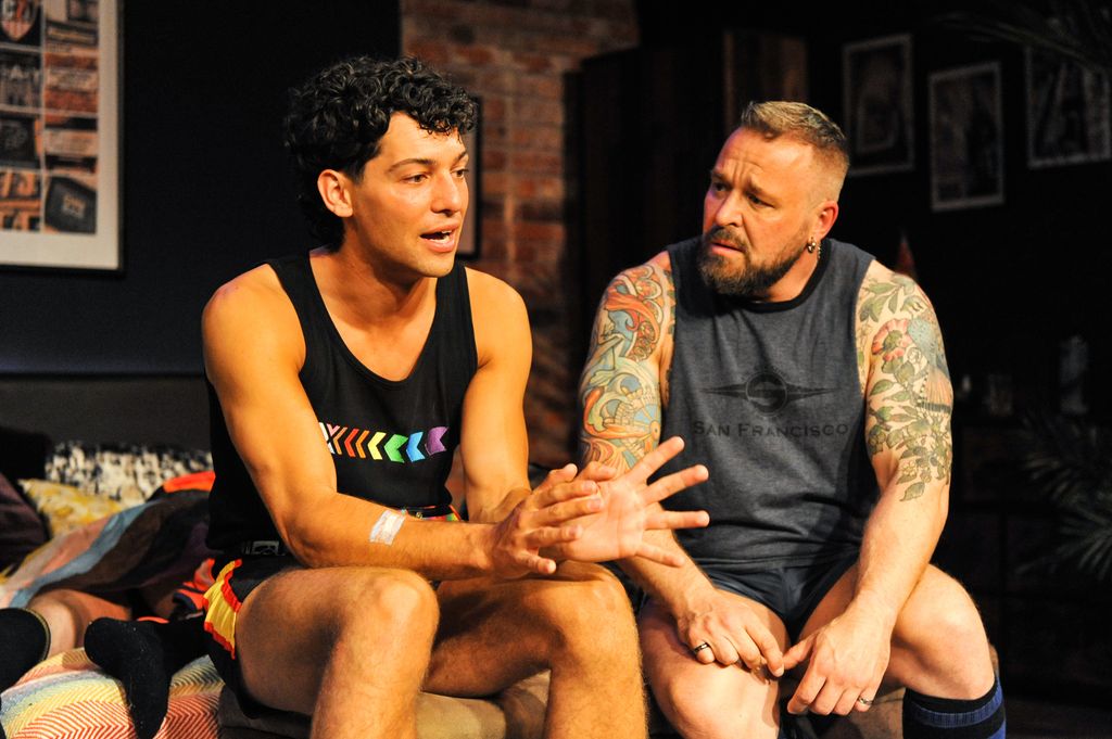 Gabriel Clark and David Paisley sitting on a bed during a production of Jock Night