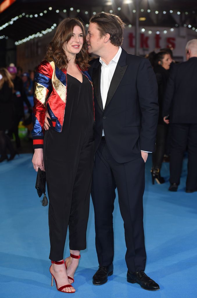 Jools Oliver with Jamie Oliver standing next to hear about to kiss on cheek