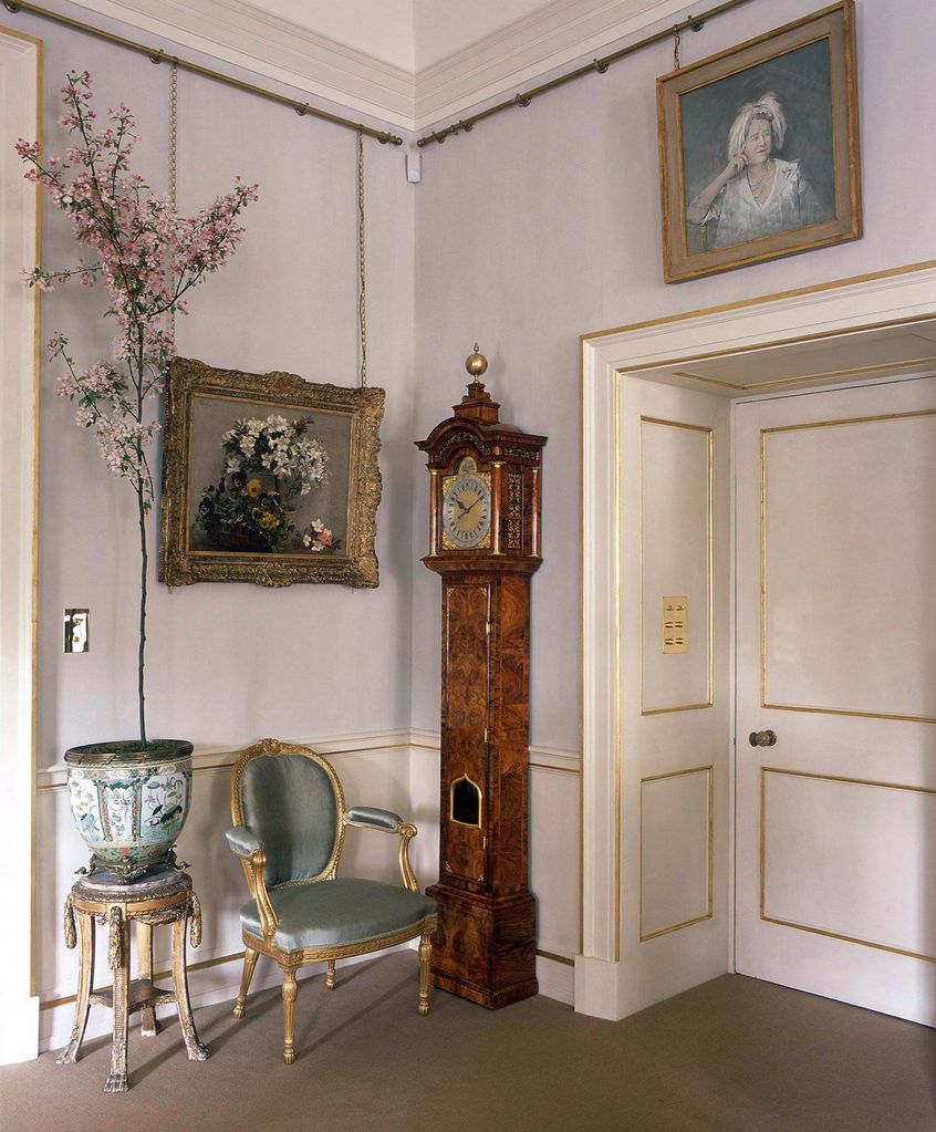 A corner of Clarence House with a grandfather clock and a portrait of the late Queen Mother