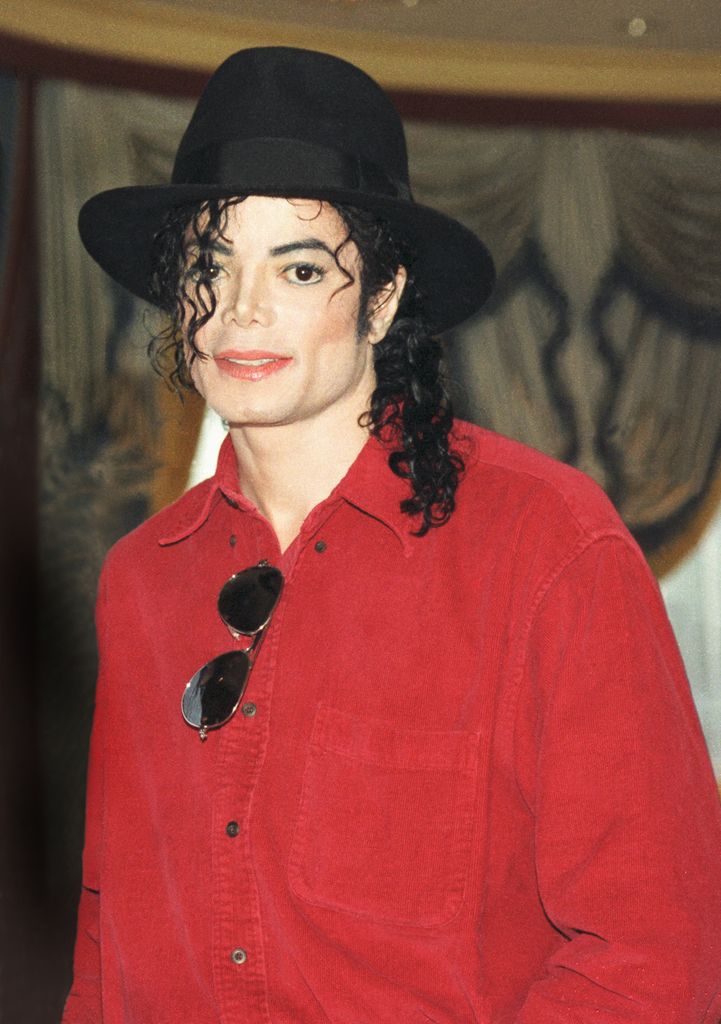 Michael Jackson in a red shirt and hat smiling