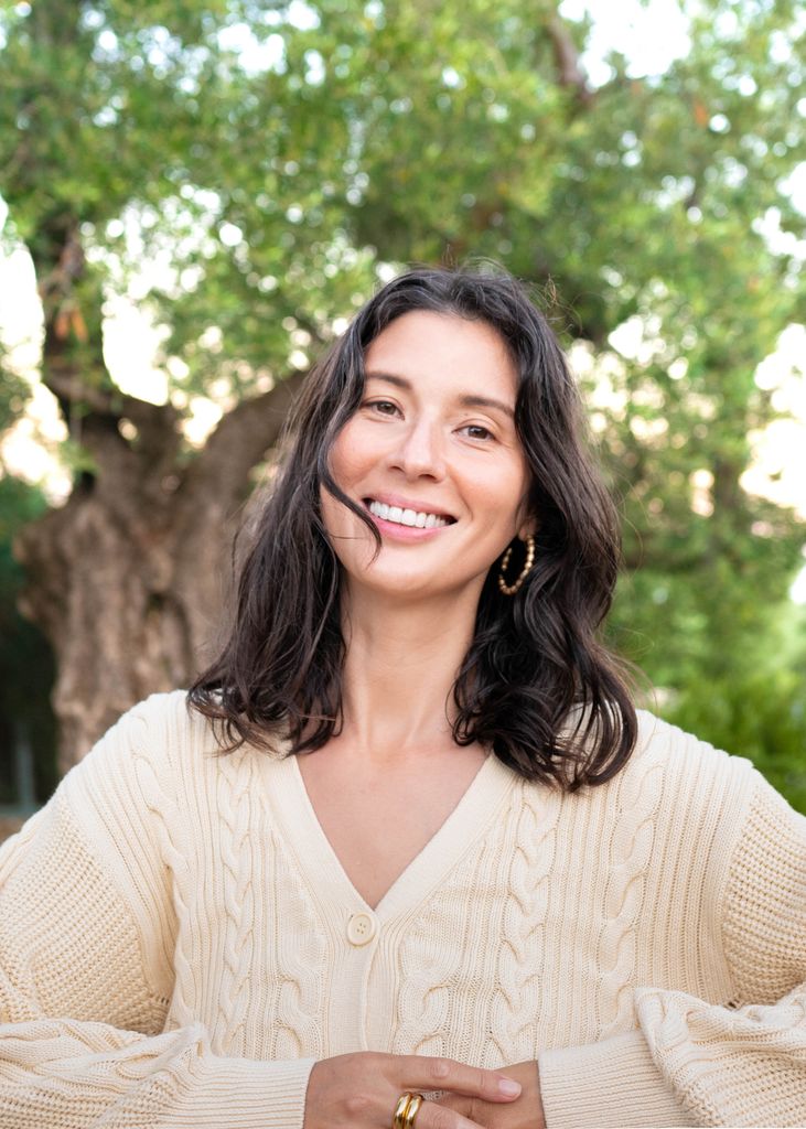 photo of a brunette woman in a cream cable knit jumper 