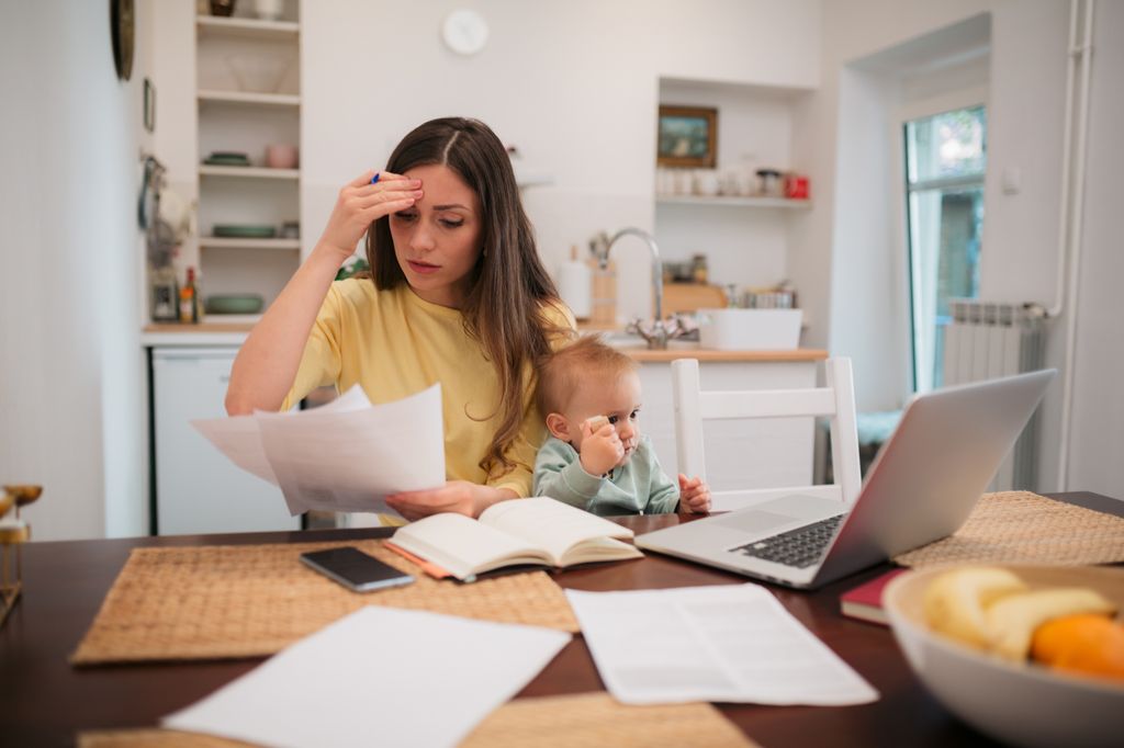 stressed woman working at home with baby on lap