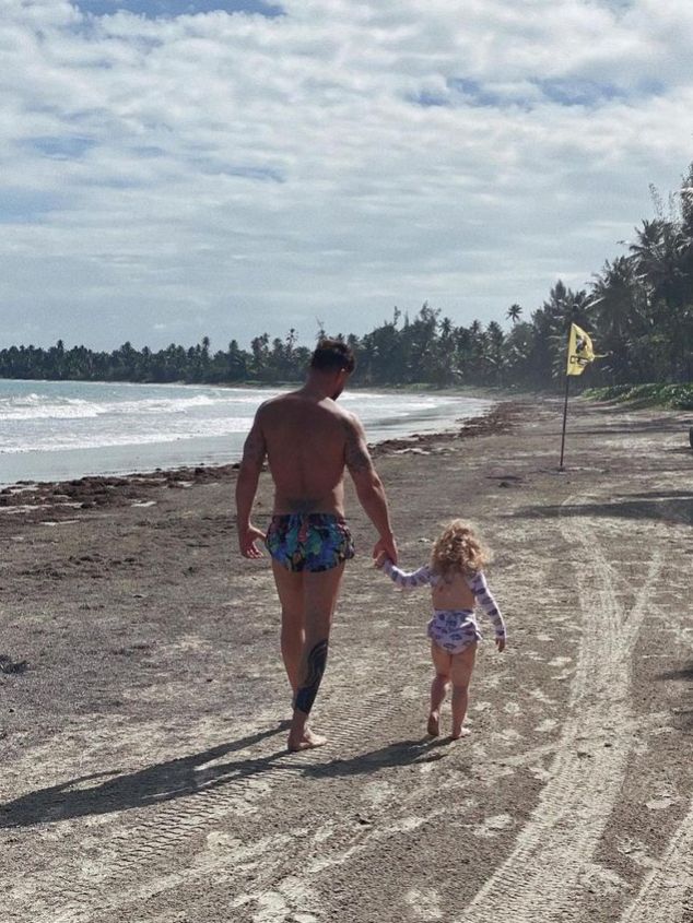 Ricky Martin and young girl walking on beach