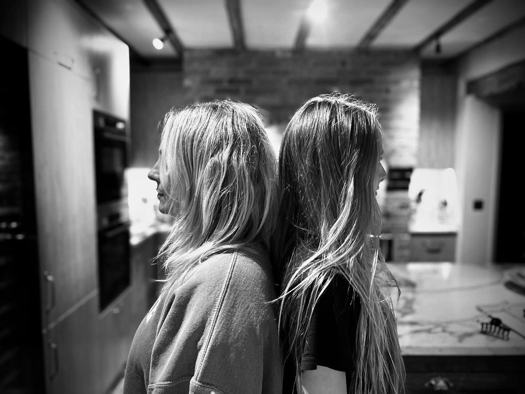 mother and daughter posing back-to-back in kitchen 