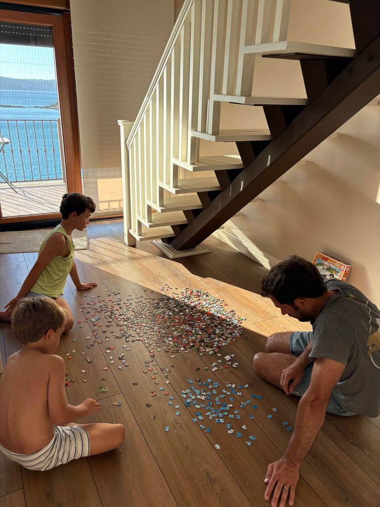 A father and his two sons doing a puzzle on the floor