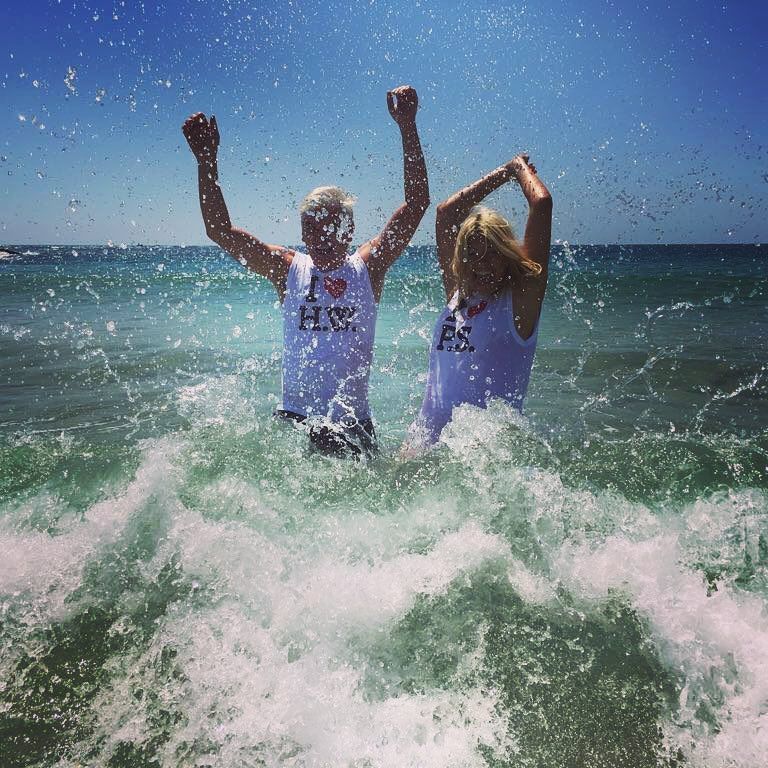 Holly and Phillip throw up hands in the sea on holiday