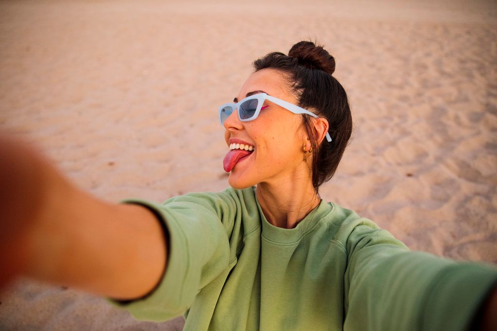 Happy woman taking selfie on the beach