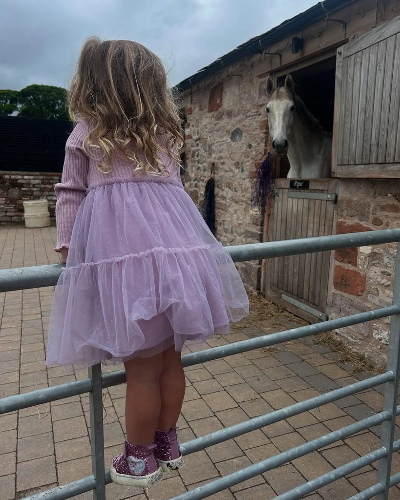 Helen Skelton's daughter Elsie in a pink dress looking at horses