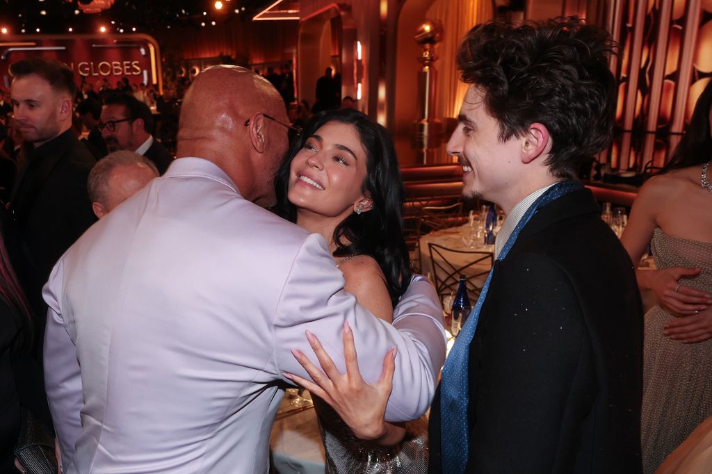 Dwayne Johnson hugging Kylie Jenner with Timothee Chalamet standing by at the Golden Globes