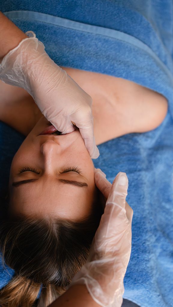 A woman getting a buccal massage in a blue towel