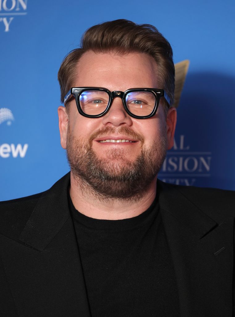 James Corden smiles for photographs wearing black glasses as he attends RTS Awards