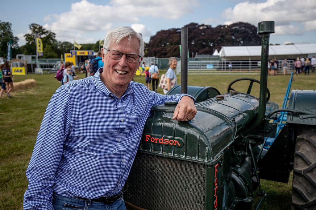 John Craven in a checkered shirt resting his arm on a tractor
